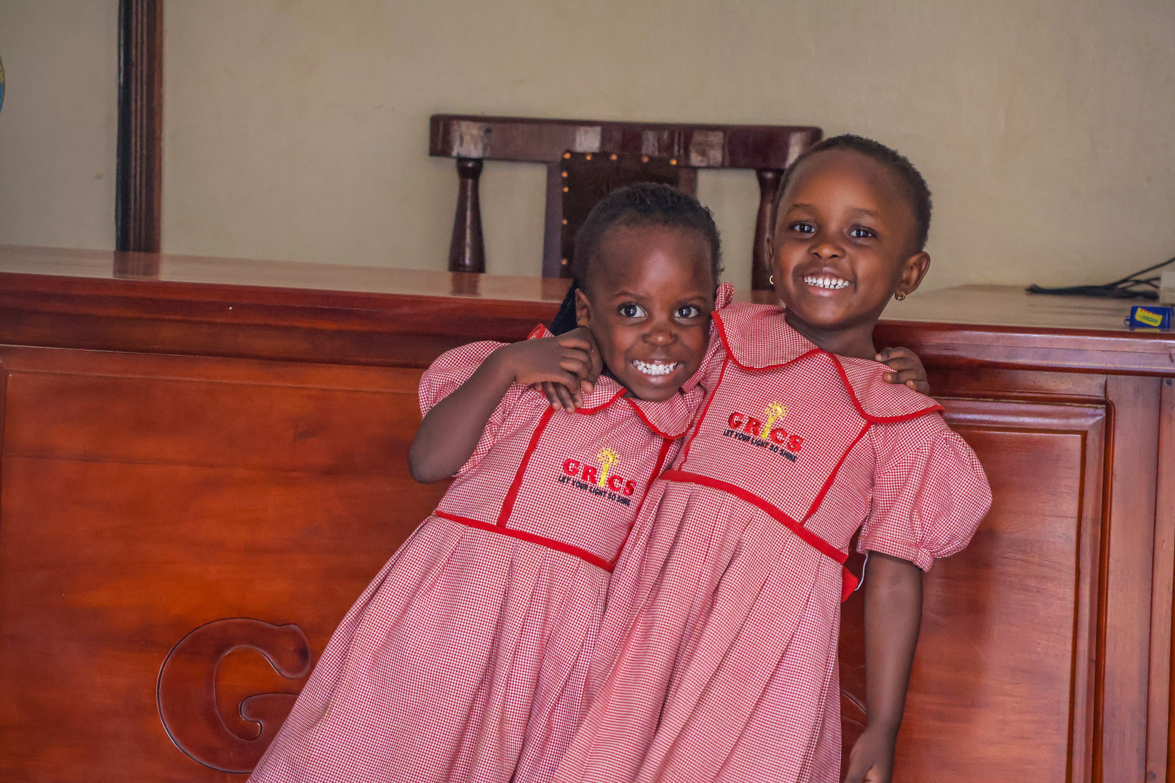 Two young GRICS learners in uniform posing arm in arm